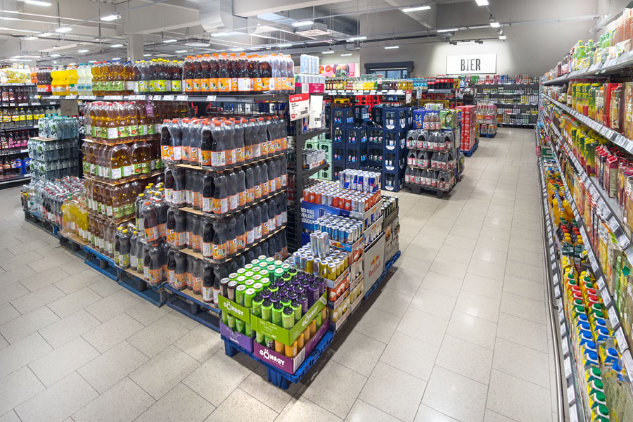 Getränkeabteilung im Supermarkt mit Paletten voller Softdrinks und Regalen