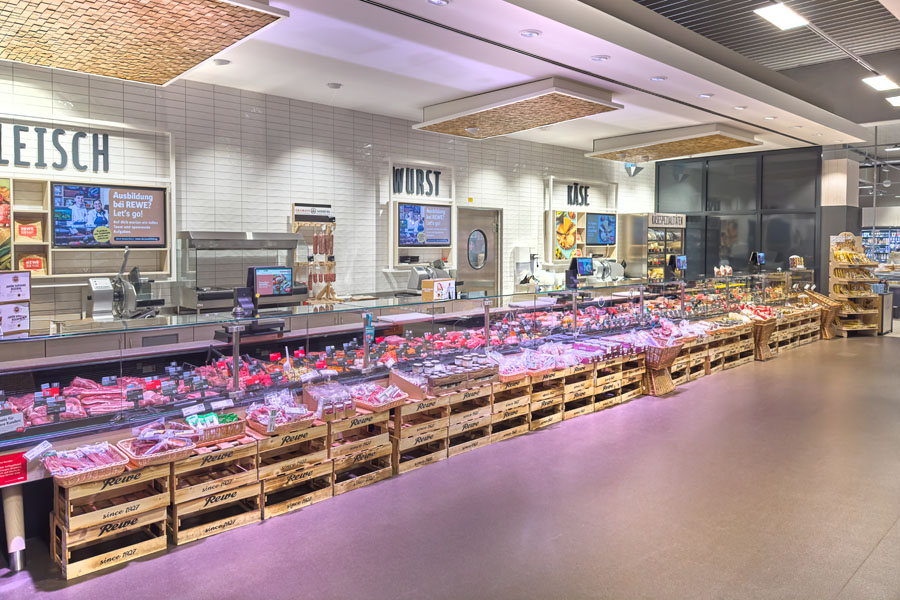 Fleisch- und Wursttheke im Supermarkt mit Kühlvitrinen und Auslage.
